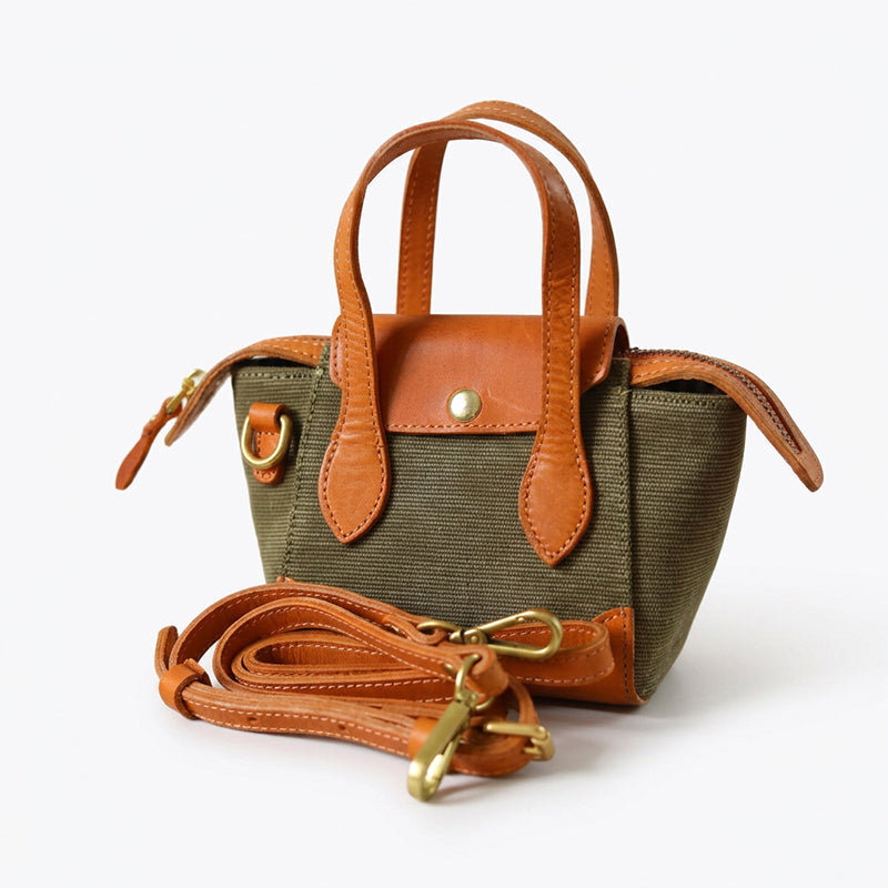 Mini canvas tote bag with tan leather trim and brass hardware, handheld style