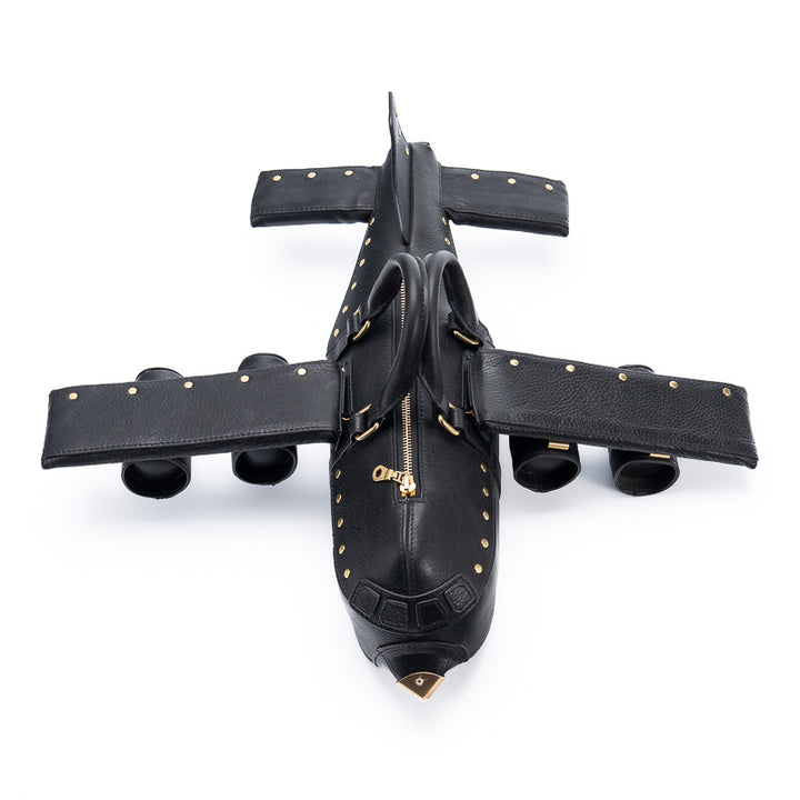 Black airplane-shaped leather handbag with gold studs and brass nose cone, top view