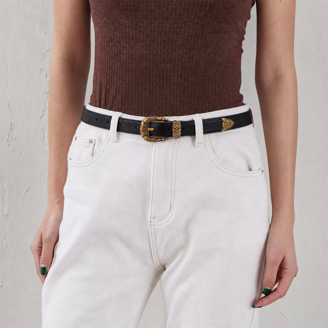 Woman wearing a black leather belt with an ornate gold-tone buckle and white jeans.