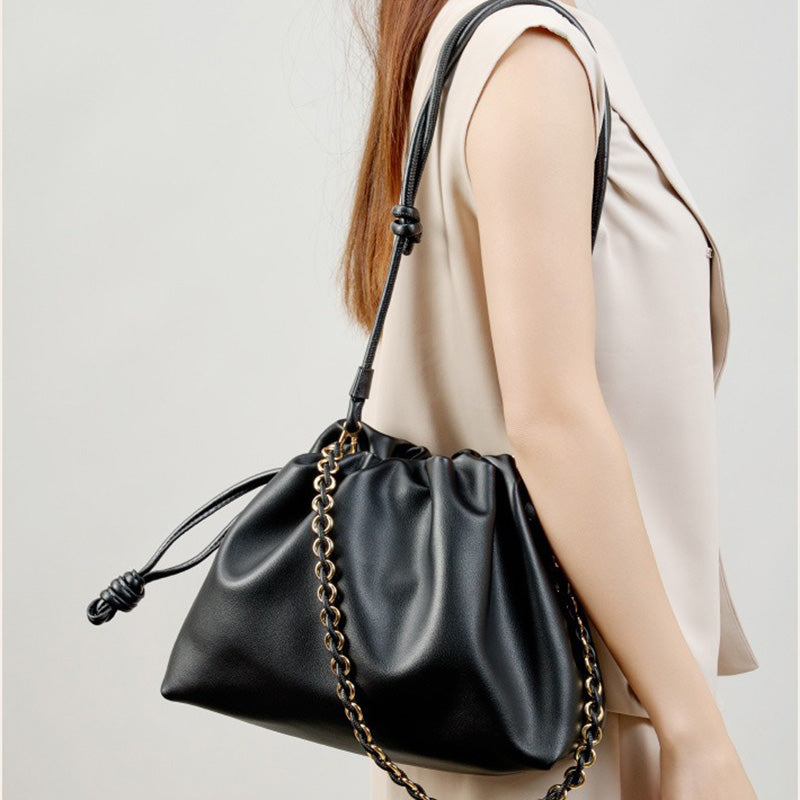 A black cowhide leather bucket bag with a soft ruched shape and gold-tone chain strap.