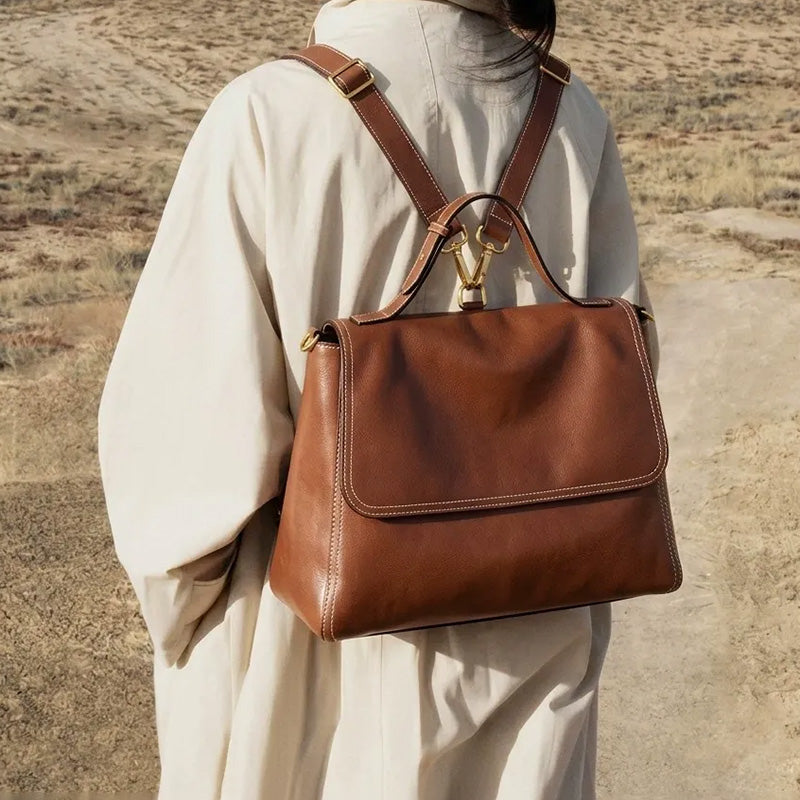 Woman wearing a brown convertible leather backpack with a flap closure and top handle.