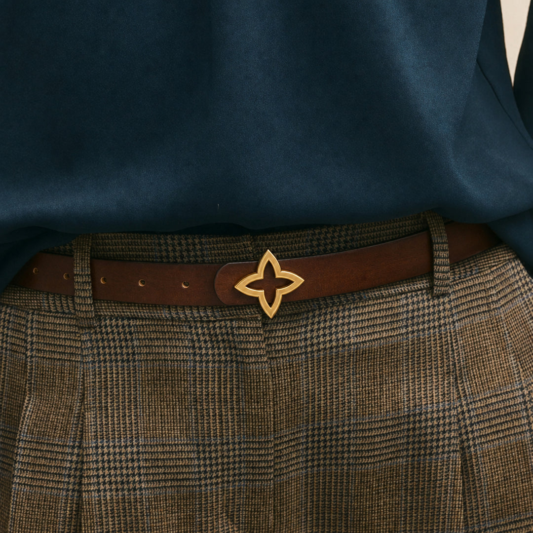 Brown leather belt with a gold-tone star buckle worn with checked trousers.