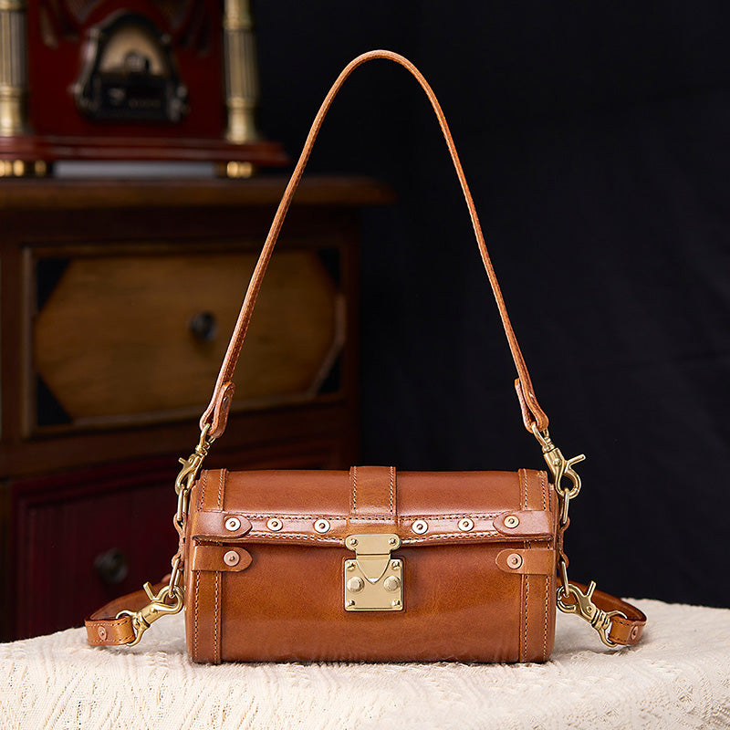Brown vegetable tanned leather barrel bag with metal latch lock and dual detachable shoulder straps