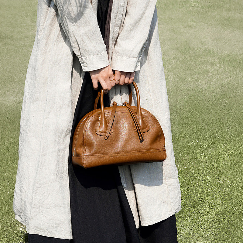 Brown vegetable tanned leather Boston bag with structured silhouette and detachable crossbody strap