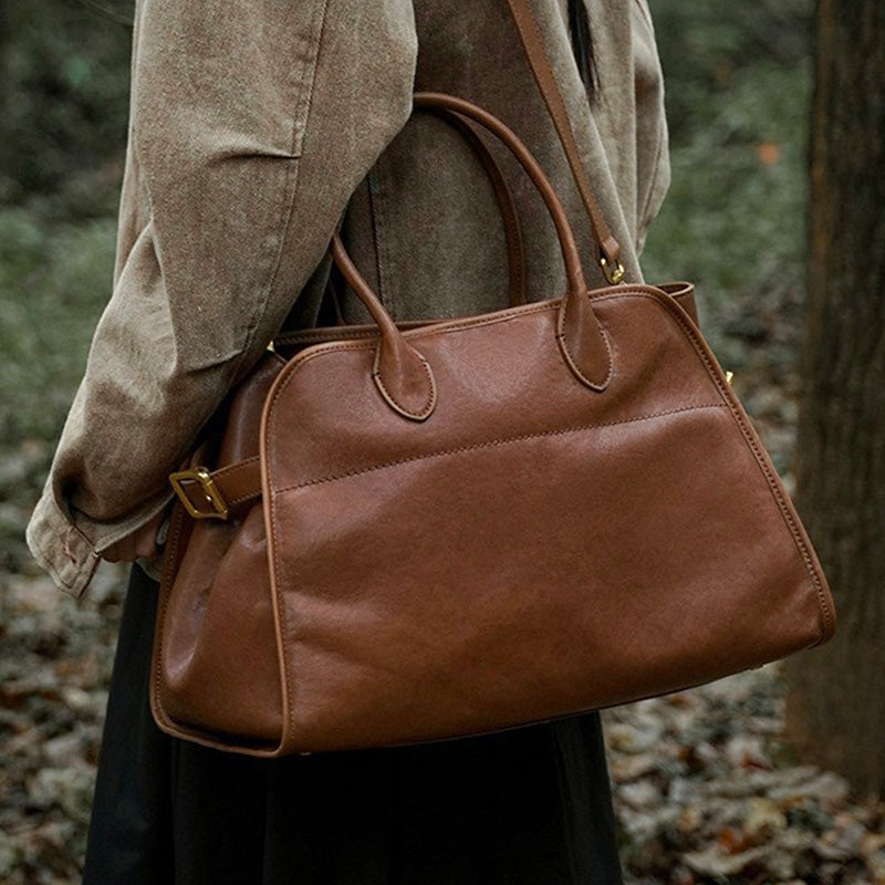 Brown vegetable tanned leather duffle bag with top handles and detachable shoulder strap