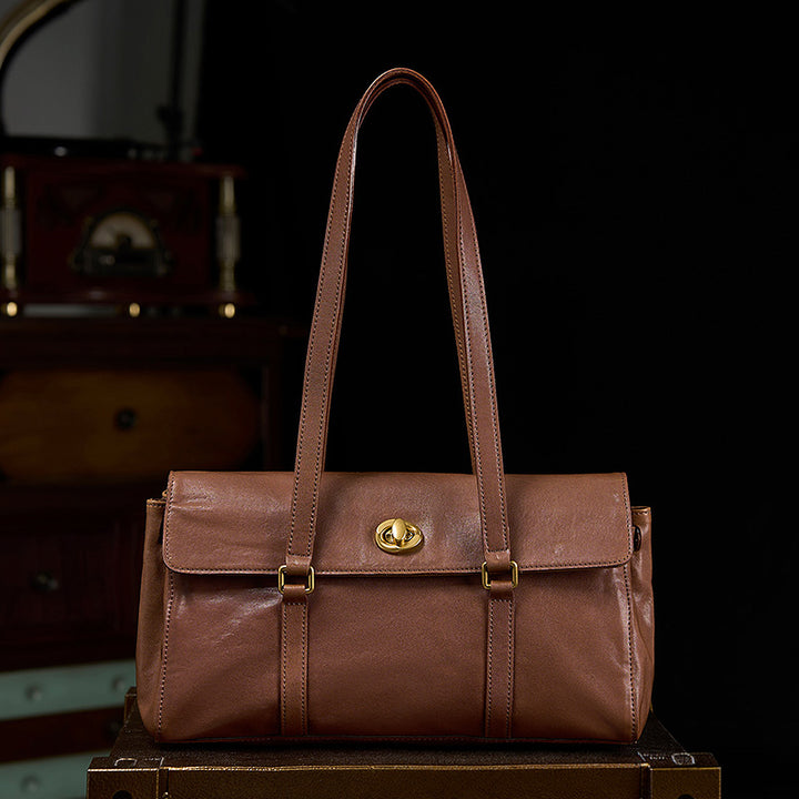 Brown vegetable tanned leather structured satchel with gold turn-lock closure and shoulder strap