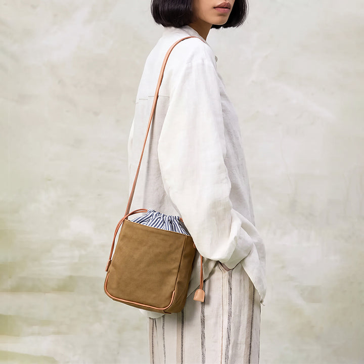 Mini canvas bucket bag in khaki worn shoulder with leather strap