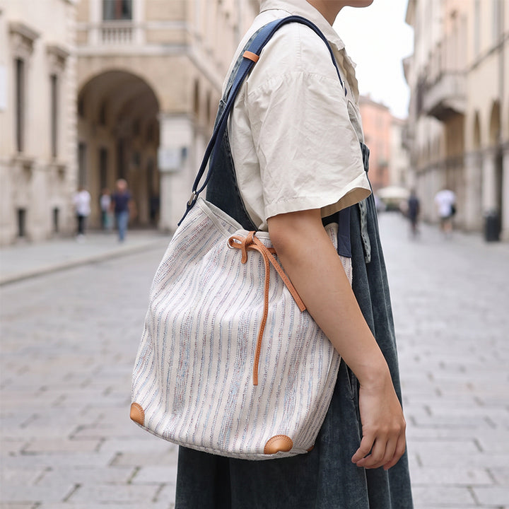 Striped canvas bucket bag worn shoulder on city street