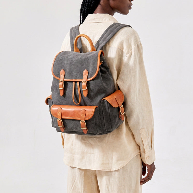 Woman wearing a vintage canvas drawstring backpack with leather trim and brass buckles