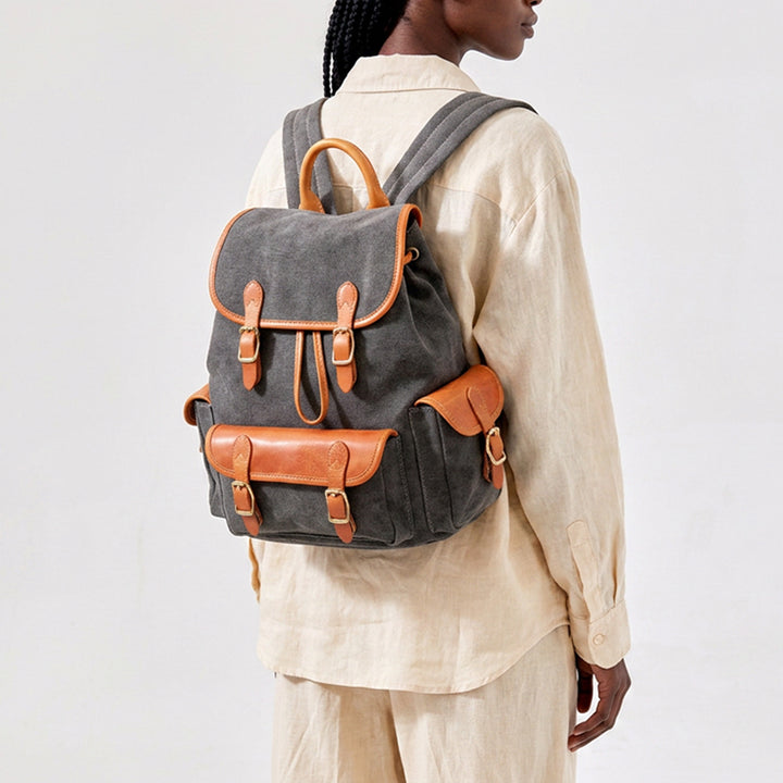 Woman wearing a vintage canvas drawstring backpack with leather trim and brass buckles