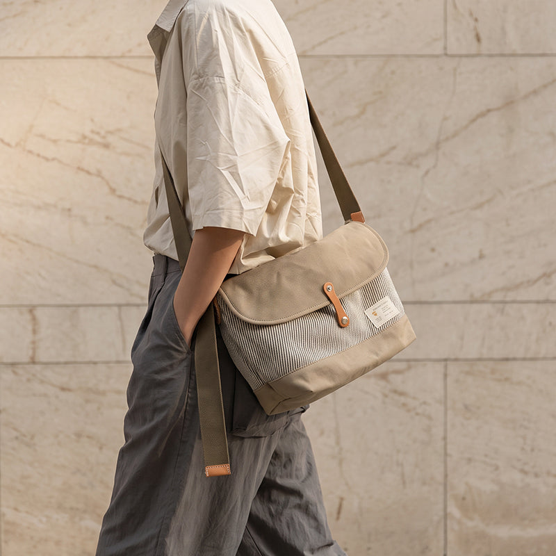 Khaki canvas messenger bag with hickory stripe worn crossbody, casual outdoor style