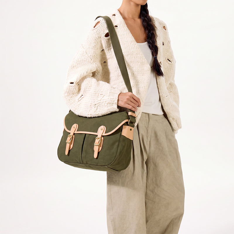 Dark green canvas messenger bag with leather buckle straps worn shoulder