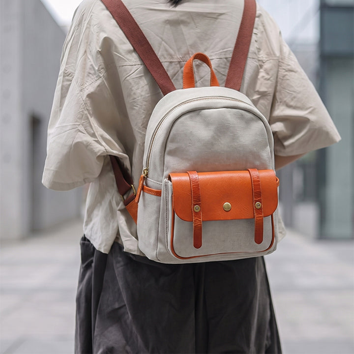 Woman wearing a vintage canvas mini backpack with leather flap pocket on street