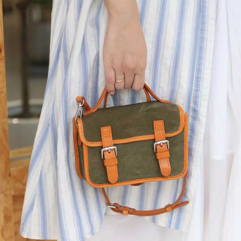 Canvas satchel bag with double buckle held by hand outdoors