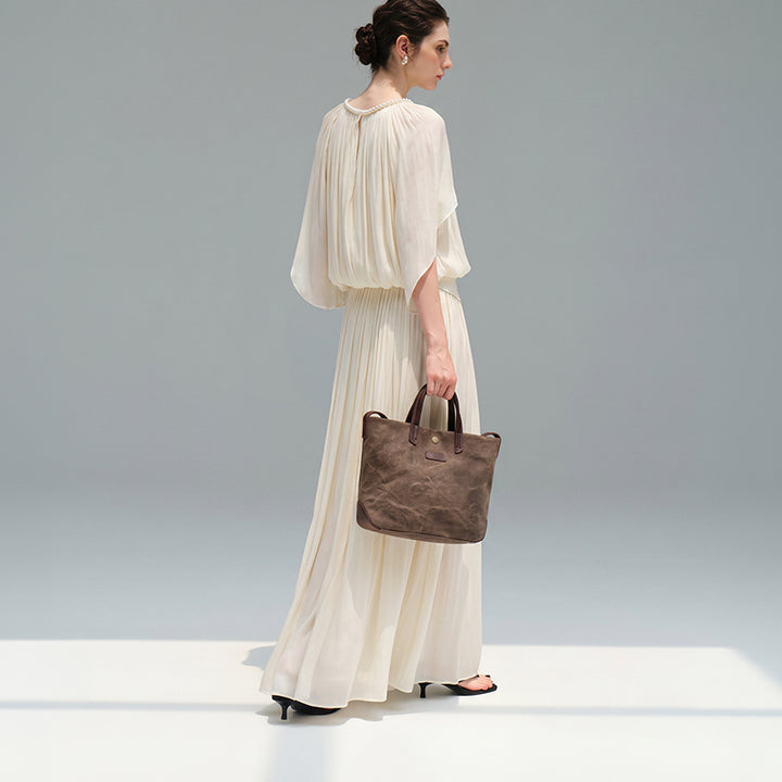 Woman carrying an coffee canvas tote bag with leather handles in a minimalist style