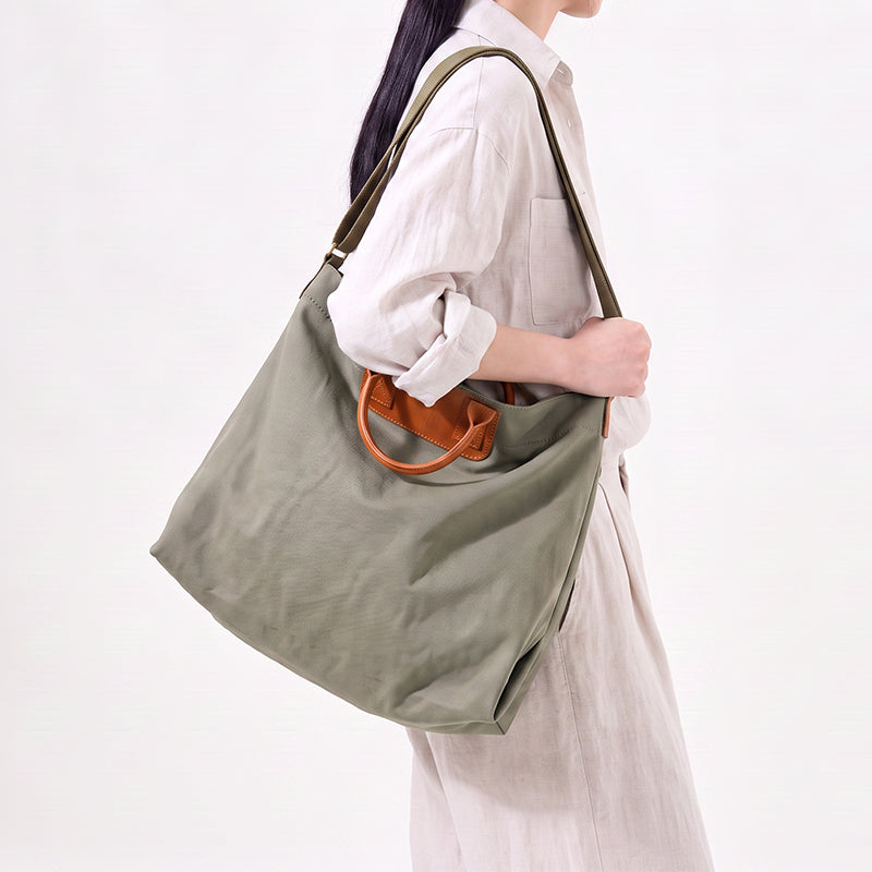 Woman carrying a large canvas tote bag with oil wax leather handles over shoulder