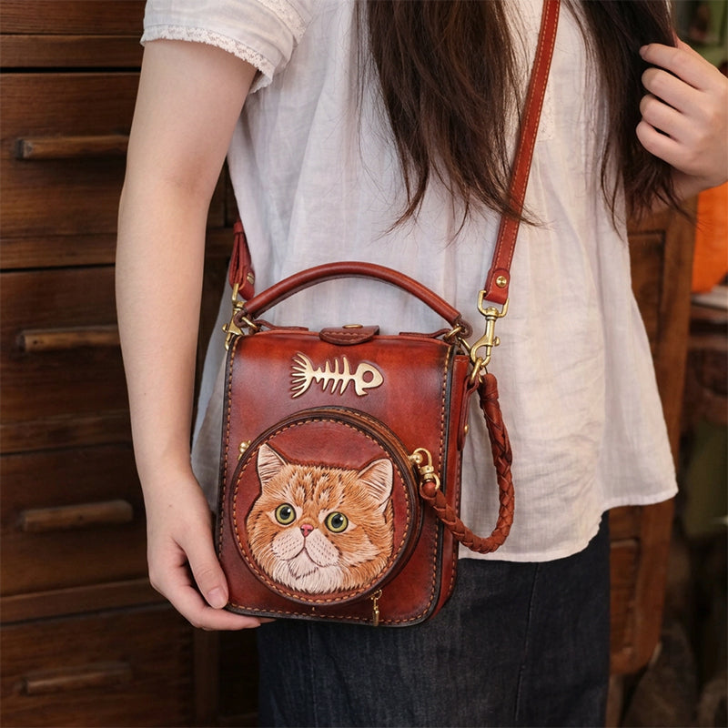 Model wearing a cat leather crossbody bag with a top handle and round cat coin pouch.