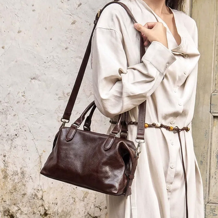 Woman wearing a coffee brown leather Boston bag over her shoulder.