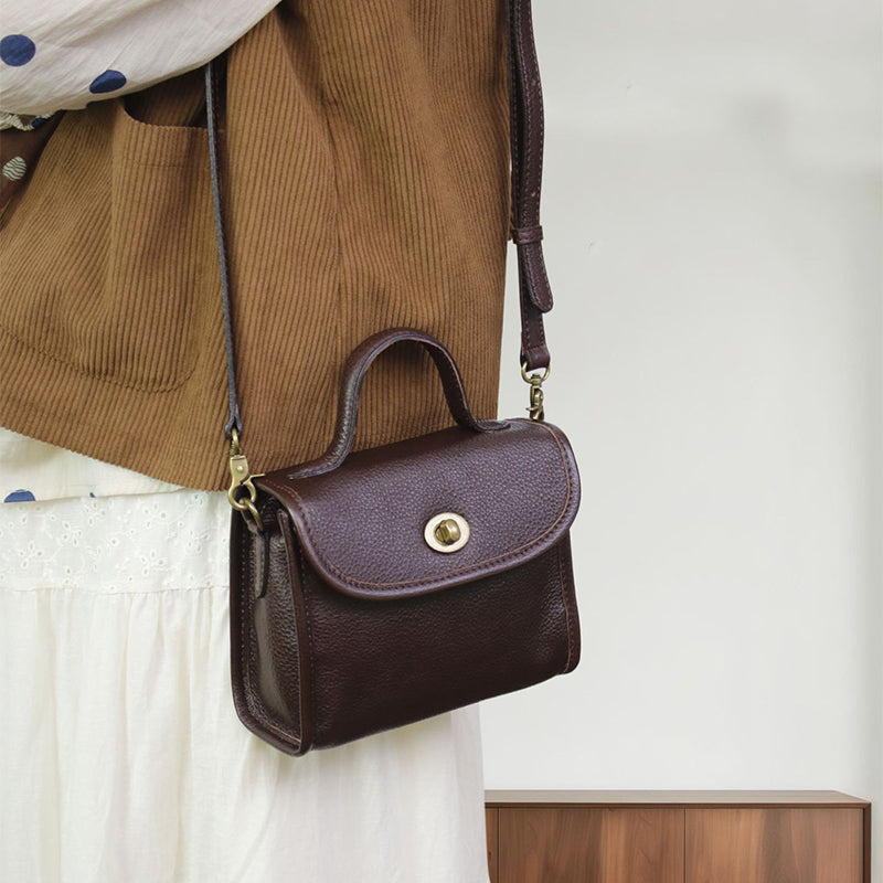 Coffee leather satchel with a top handle, turn-lock flap, and crossbody strap.