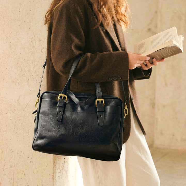 Compact black leather briefcase with gold hardware and front pocket, a lightweight convertible shoulder bag for work.