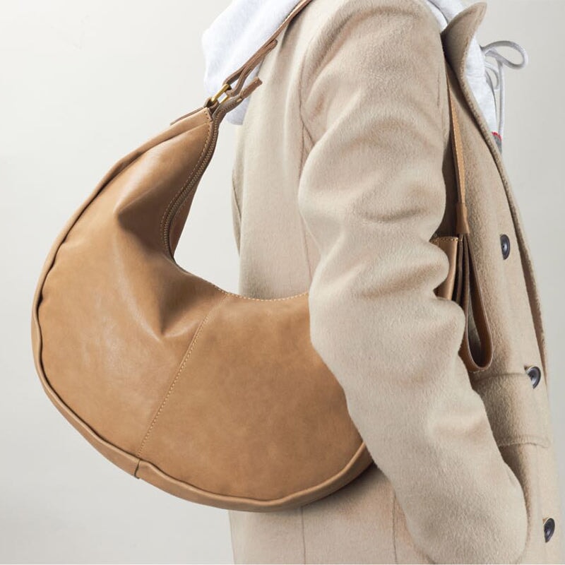 Vegetable tanned leather crescent hobo bag in apricot, worn over the shoulder.