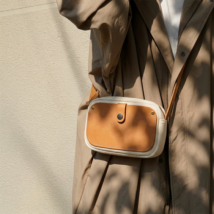 Mini canvas crossbody bag in white with leather front pocket worn as crossbody