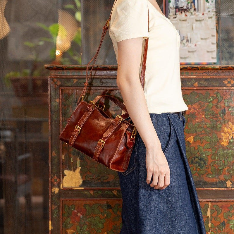 Woman wearing a brown top grain leather doctor bag with double buckle straps as crossbody, side view
