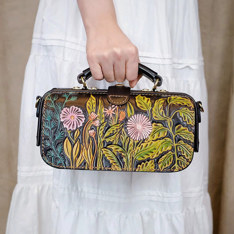 Woman holding a floral leather doctor bag with colorful carved flowers and a top handle.