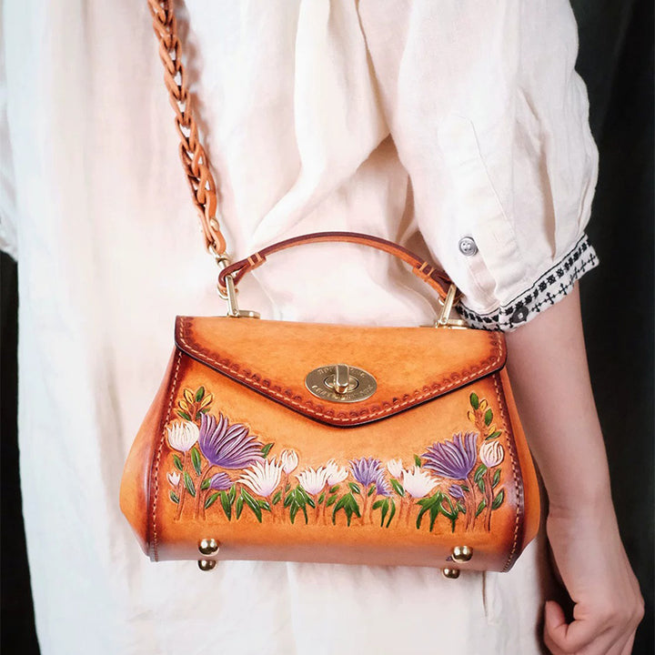 Model wearing a brown floral leather top handle bag with a braided shoulder strap.