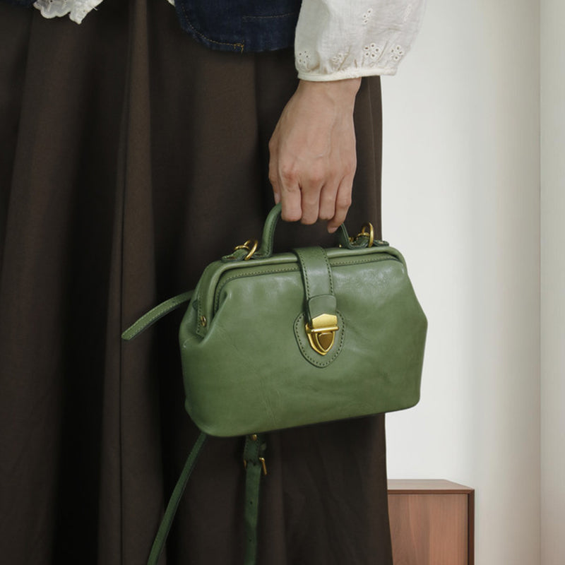 Woman carrying a green leather doctor bag by its structured top handle.