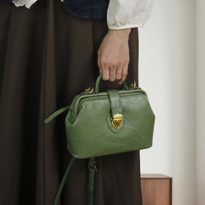Woman carrying a green leather doctor bag by its structured top handle.