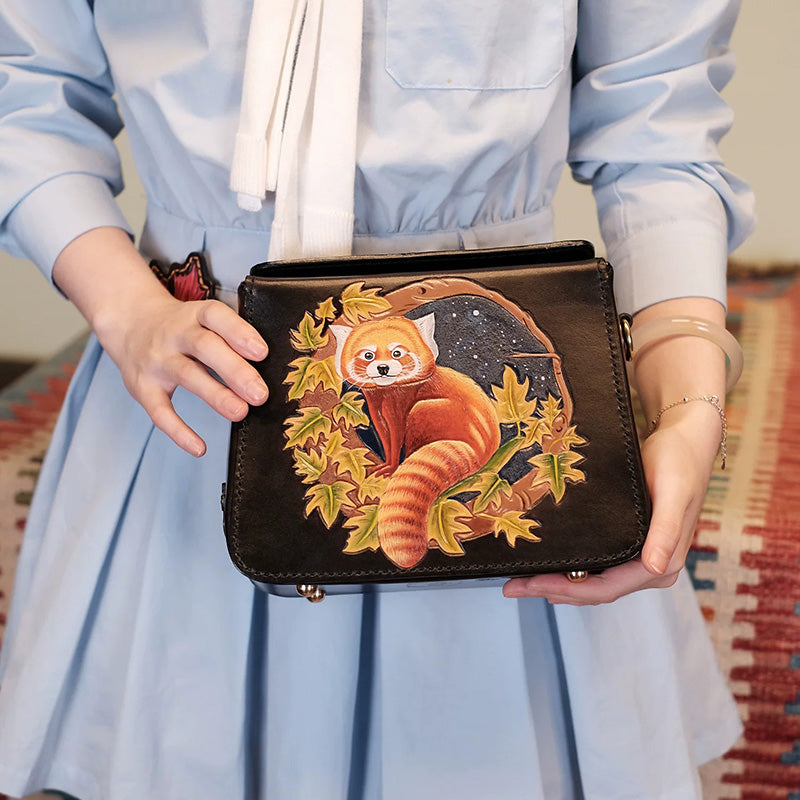 Hand-tooled black crossbody box bag with a red panda and autumn leaves.
