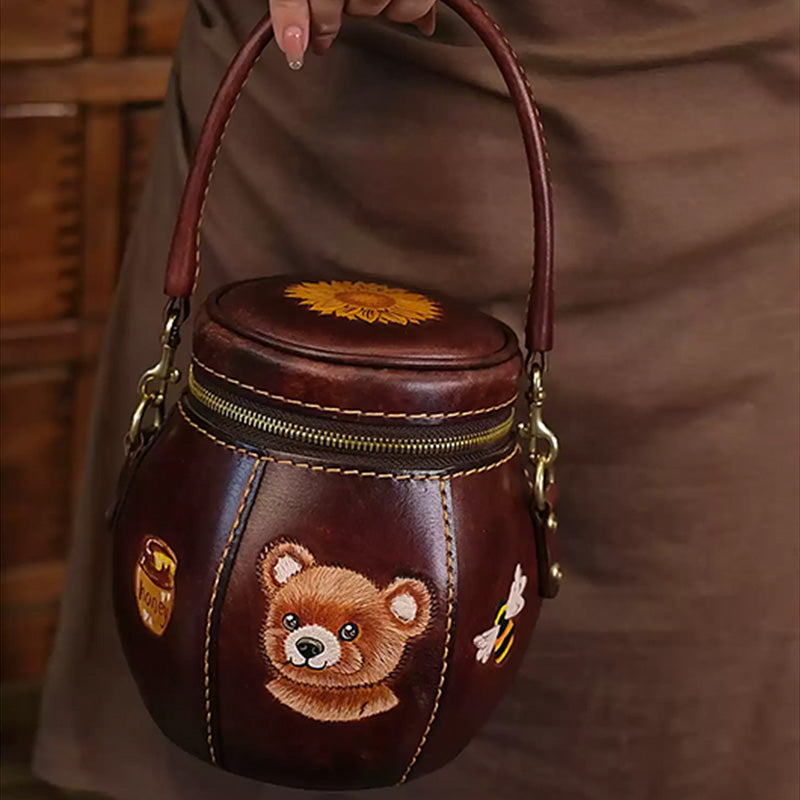 Woman carrying a honey jar-shaped leather crossbody bag with bear artwork.
