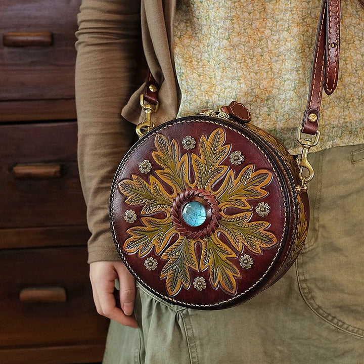 Round leather crossbody bag with oak leaf tooling and a blue labradorite centerpiece, worn at the hip.