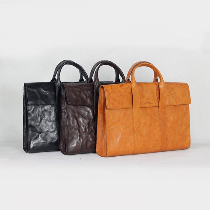 Three vegetable tanned leather briefcases in black, brown, and yellow on white background
