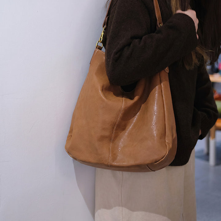 Woman wearing a large soft leather hobo bag in apricot green over her shoulder