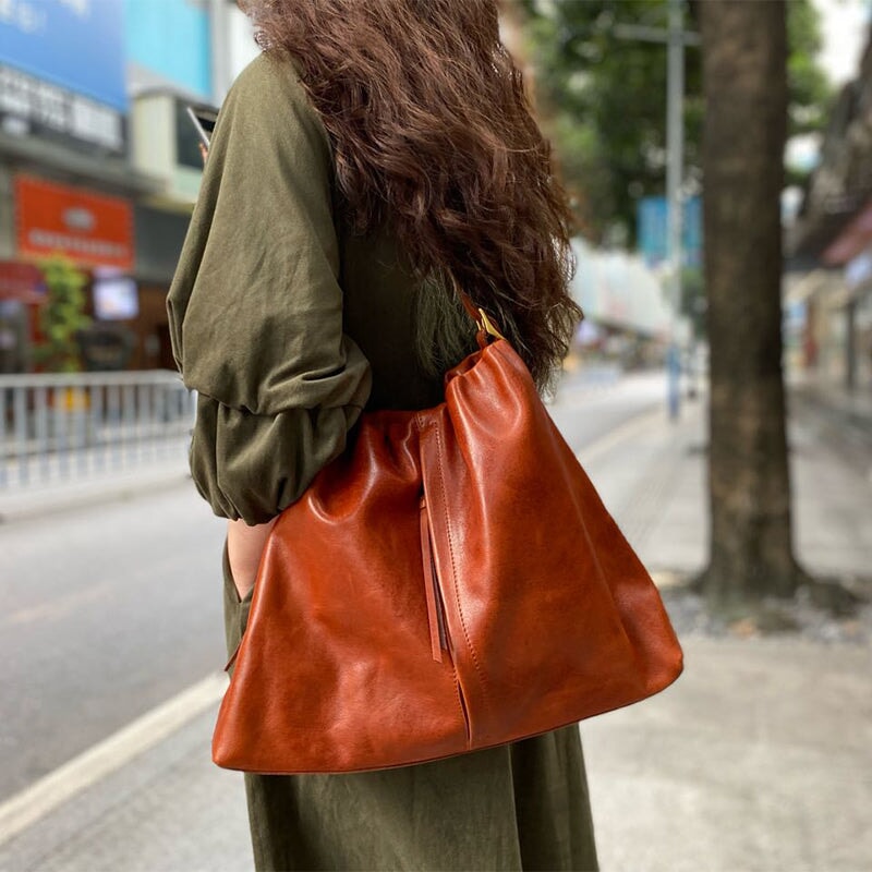 Large leather hobo bag in honey brown worn over the shoulder on a city street