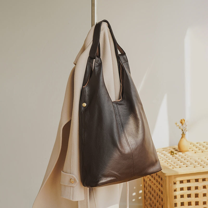 Large coffee leather hobo bag with soft slouchy silhouette hanging on a rack