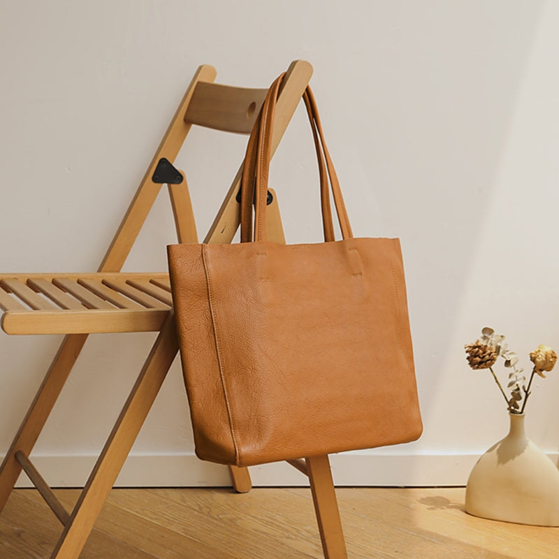 Brown large leather tote bag hanging on a wooden folding chair
