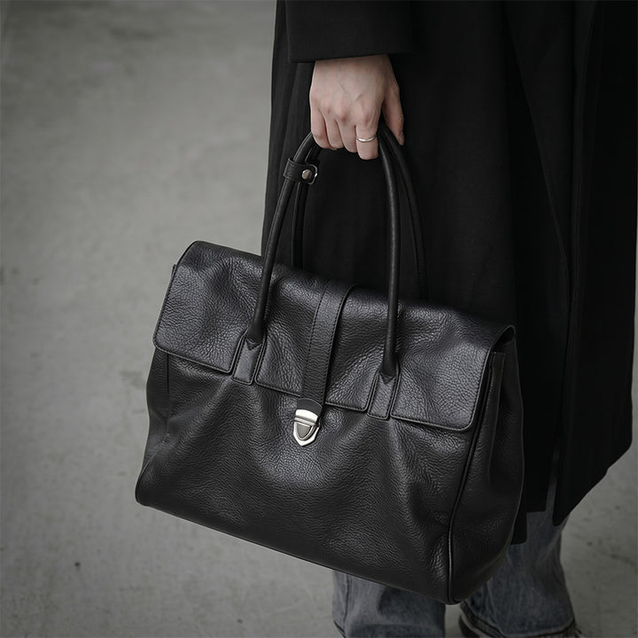 Large vegetable-tanned leather tote bag with front flap closure, in black.