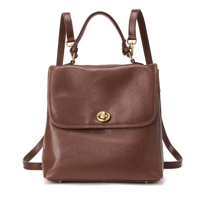 A brown vegetable tanned leather backpack with dual compartments and gold hardware, shown from the front
