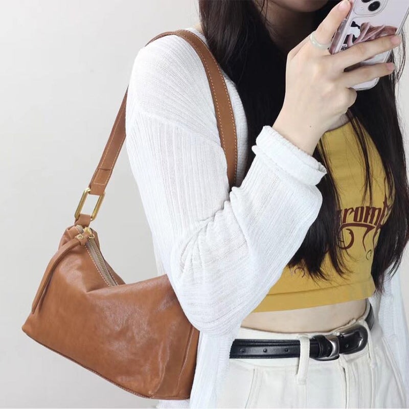 Woman carrying a vegetable tanned leather baguette bag in apricot as an underarm bag