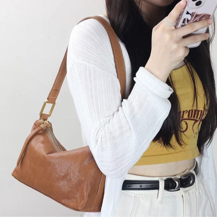 Woman carrying a vegetable tanned leather baguette bag in apricot as an underarm bag