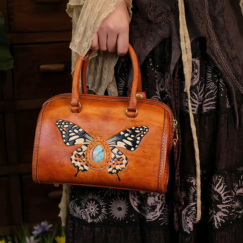 Woman holding a hand-carved leather Boston bag with butterfly and labradorite design