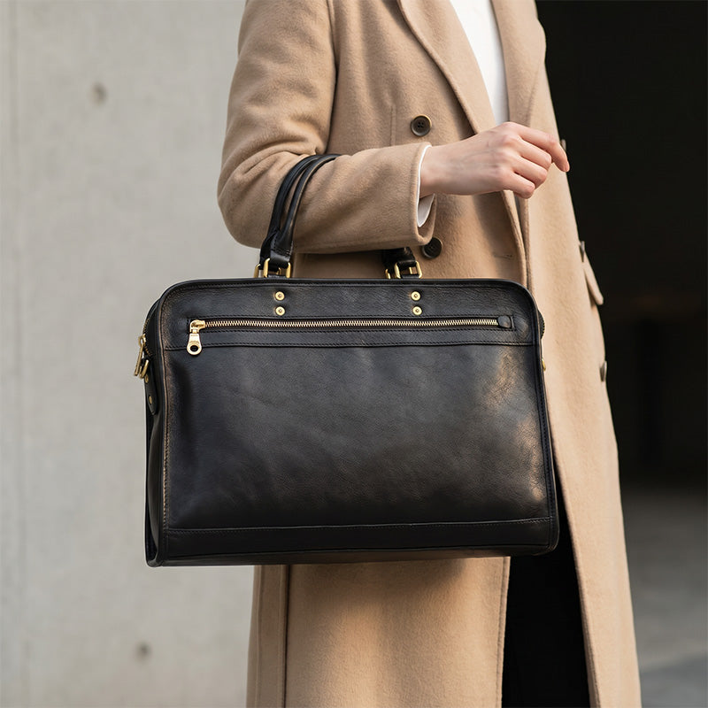 Black vegetable-tanned leather briefcase with dual handles and front zip pocket, ideal as a laptop bag for work.