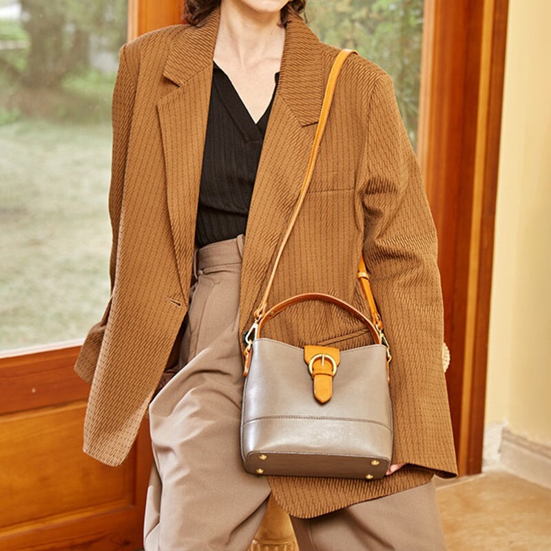 Vegetable tanned leather bucket bag in gray with gold buckle strap and top handle
