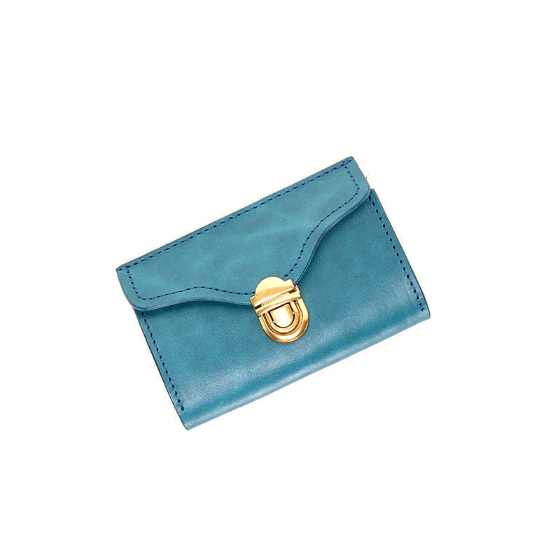 Light blue vegetable tanned leather card wallet with gold push-lock clasp, flat lay