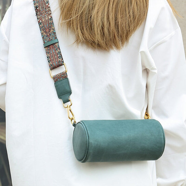 Woman wearing a green leather cylinder crossbody bag with boho wide strap