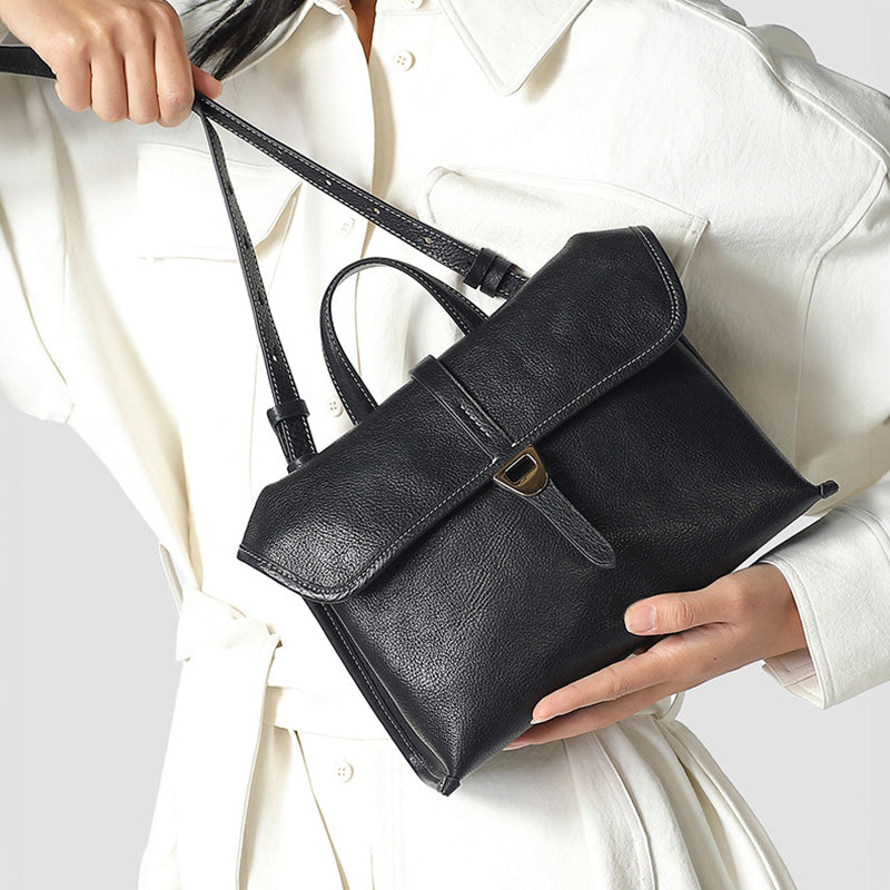 Black vegetable-tanned leather satchel bag with top handles and detachable crossbody strap