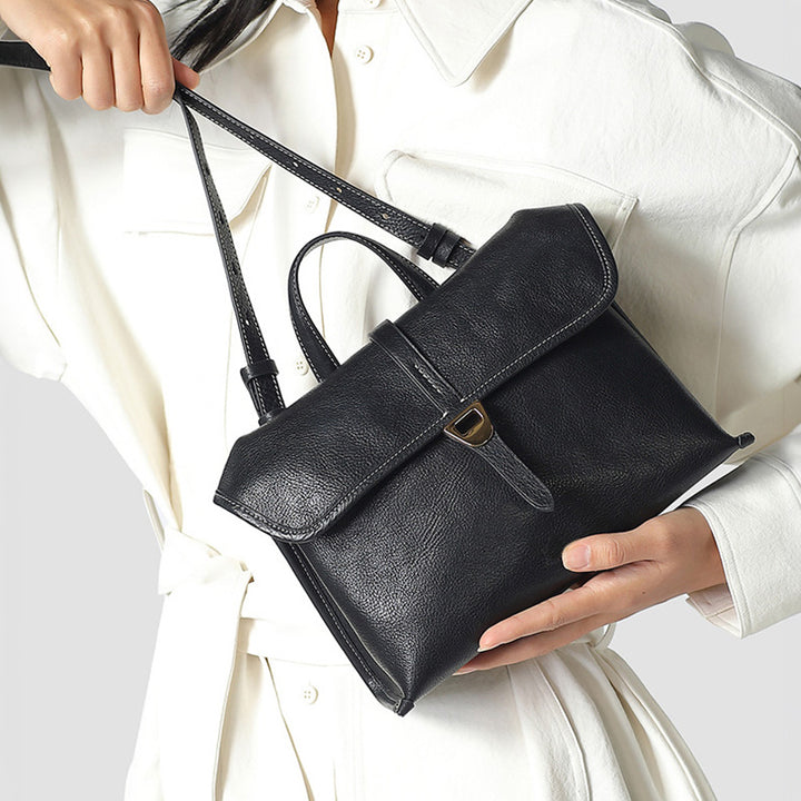 Black vegetable-tanned leather satchel bag with top handles and detachable crossbody strap